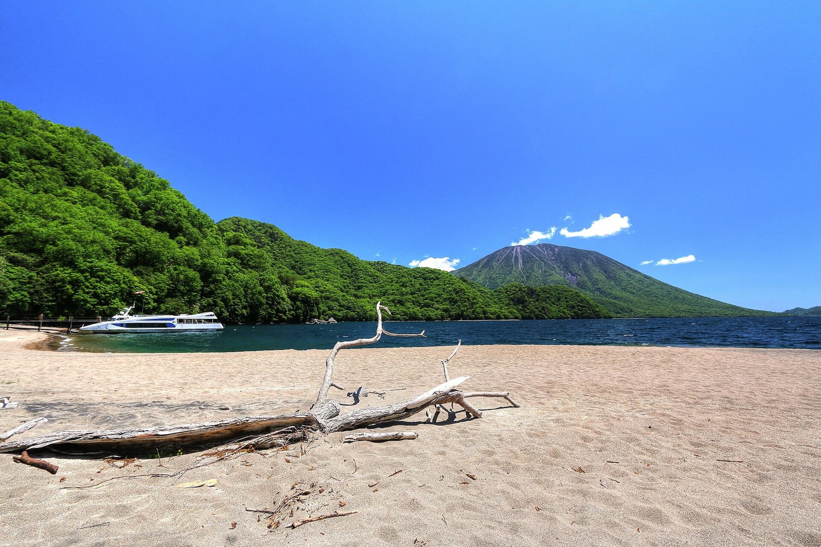 中禅寺湖西端の千手ヶ浜。緑に囲まれた湖畔と男体山、遊覧船が見える