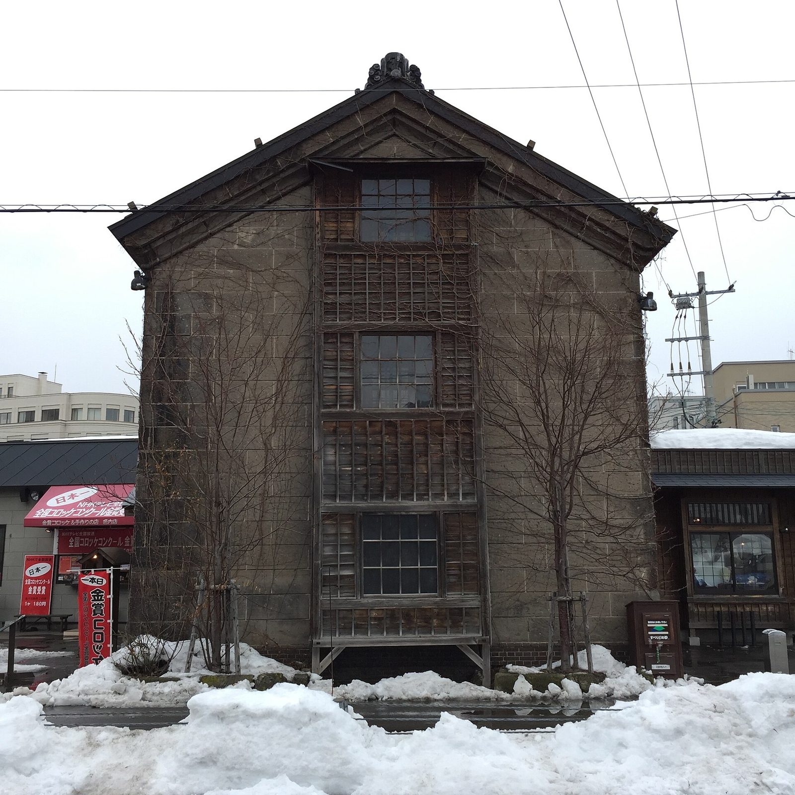 小樽堺町通り商店街に建つ石造りの建物とコロッケ店の看板