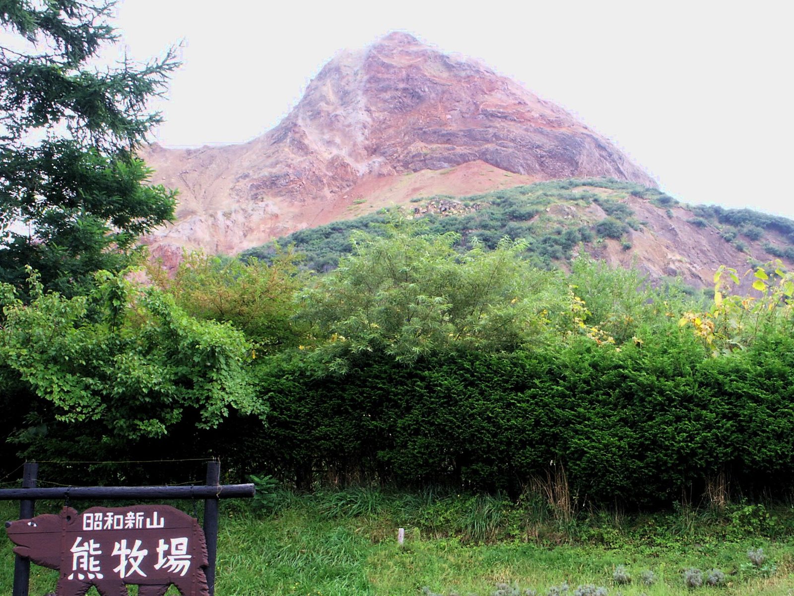 昭和新山熊牧場の入口看板と背後にそびえる昭和新山